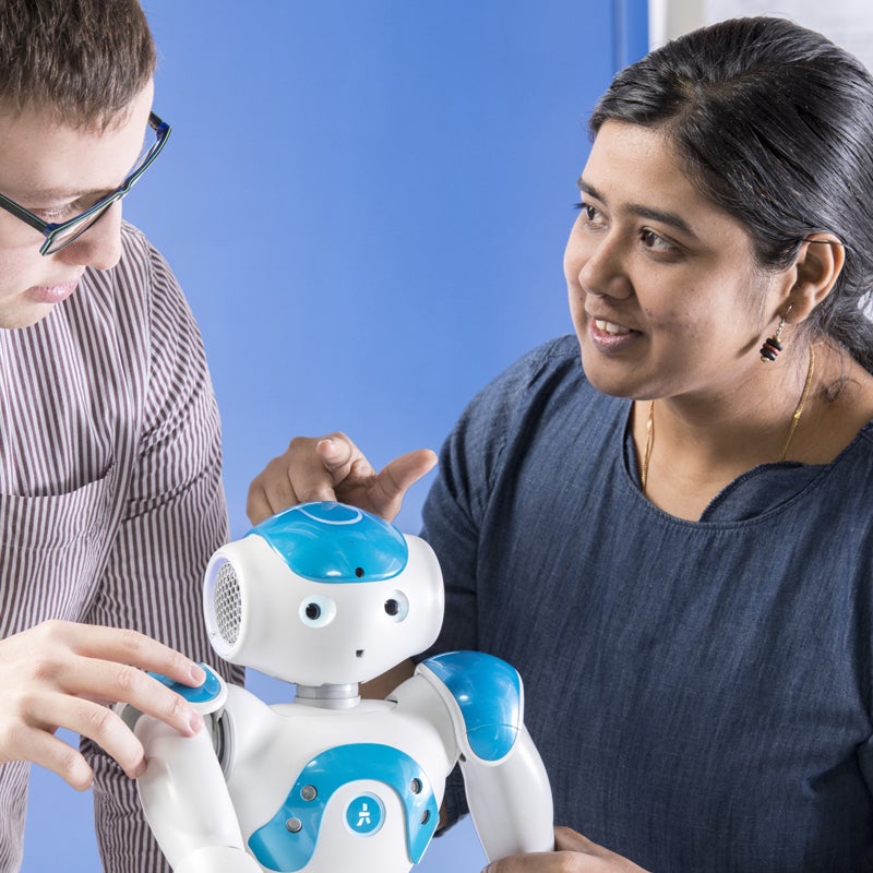 Student and faculty in a discussion with a robot