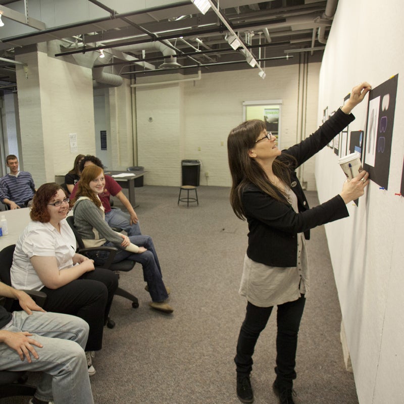 Professor putting up work on a wall for a critique session