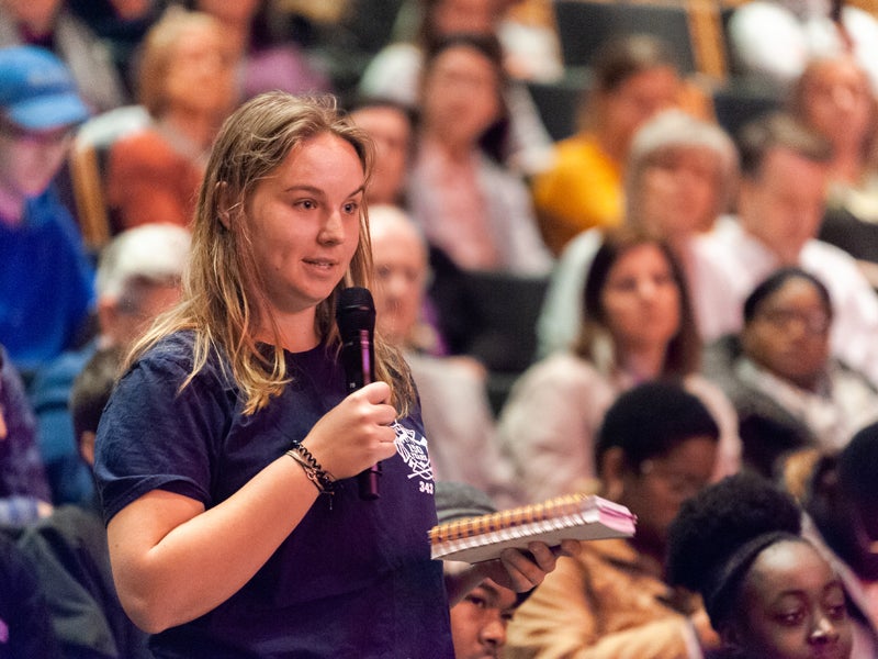 Student asking question in audience during a presentation