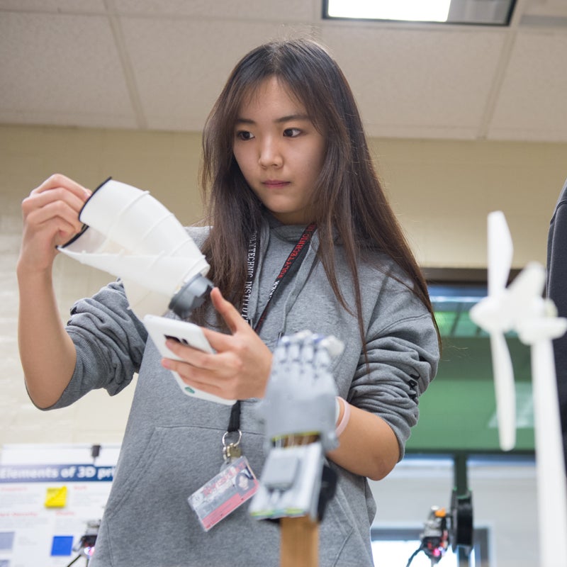 Student looking at a 3D prototype of a wind turbine