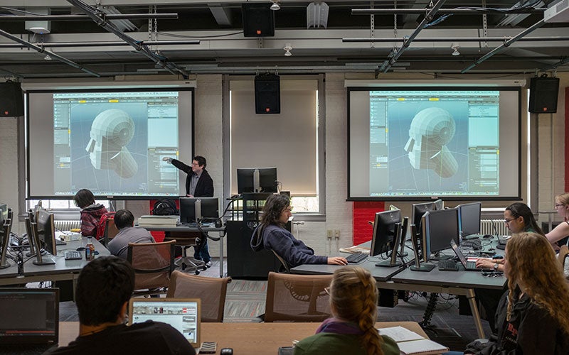 Professor Ben Chang teaching in front of two large screens