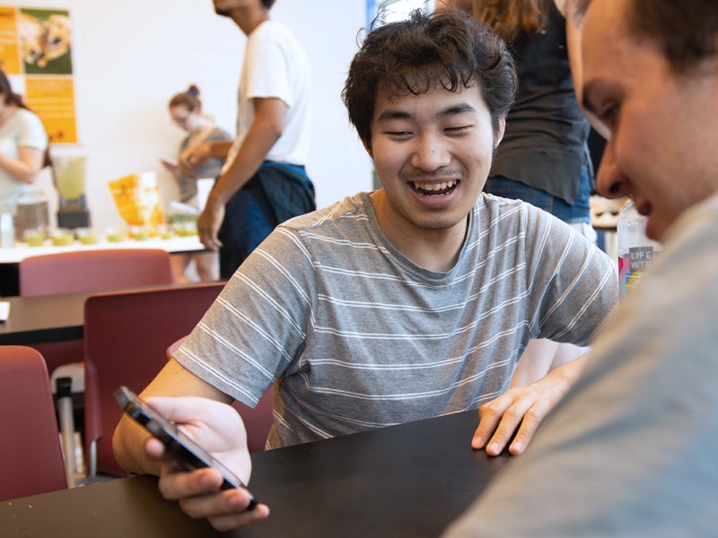 Two students looking at a smart phone having a conversation