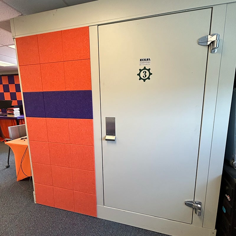 Sound-attenuated research booth with acoustic wall panels and insulated door used for cognitive and behavioral research studies.