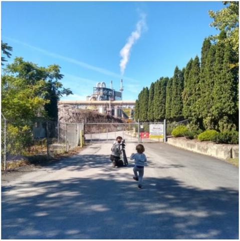 a child running towards someone photographing an industrial complex