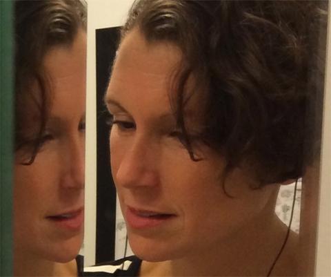 a caucasian woman with brown hair, seemingly, looking at her reflection